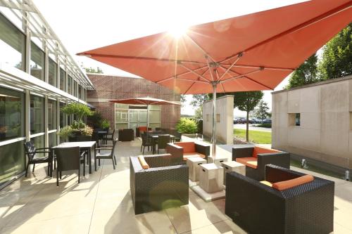 a patio with tables and chairs and an umbrella at I Hotel and Illinois Conference Center - Champaign in Champaign