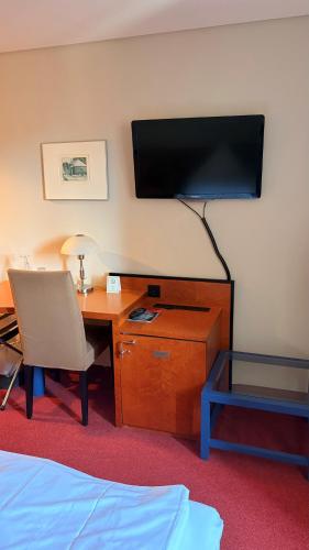 a hotel room with a desk and a television on the wall at Hotel zum Ritter in Fulda