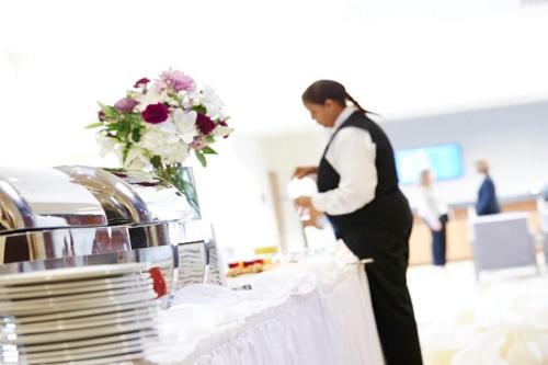 a woman standing in front of a table with plates at I Hotel and Illinois Conference Center - Champaign in Champaign