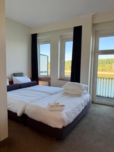 two beds in a room with two windows at Hotel am Rhein in Wesseling