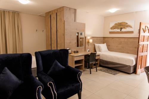 a hotel room with a bed and a desk and chairs at Wilkoppies Self Catering in Klerksdorp