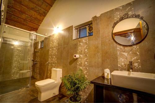a bathroom with a toilet and a sink and a mirror at Brown Town Resort & Spa in Hyderabad