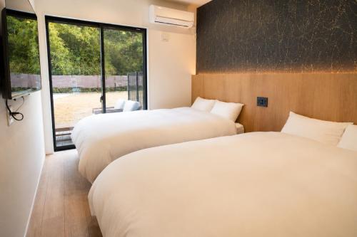 two beds in a room with a window at Awaji Play Resort in Minamiawaji