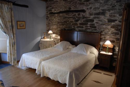 a bedroom with two beds and a brick wall at Casa Grande da Ferreria de Rugando in Rugando