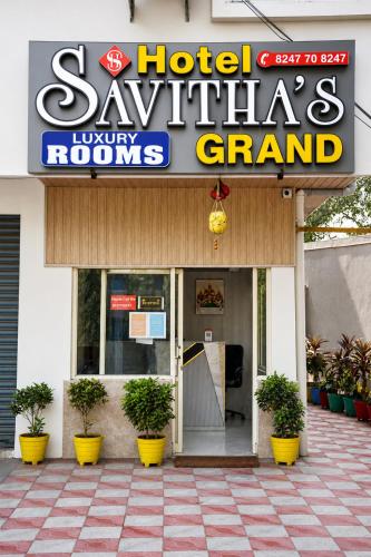 a sign for a hotel with potted plants in front of it at Hotel Savithas Grand in Vijayawāda