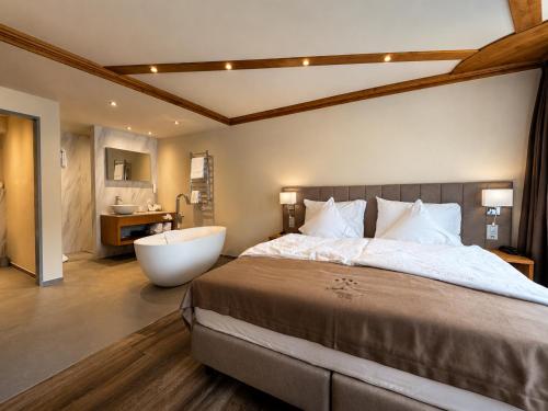 a bedroom with a large bed and a bath tub at Hotel Beau Rivage in Zermatt