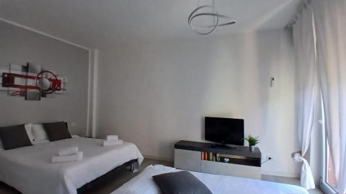 a white room with two beds and a tv at MilanoValery3 in Milan