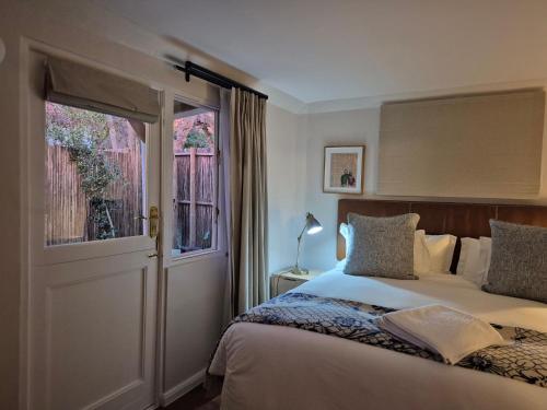 a bedroom with a bed and a window and a door at Petit Ermitage in Franschhoek