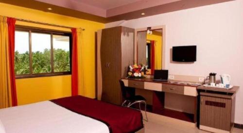 a hotel room with a bed and a desk and a window at Hotel Colva Kinara in Colva