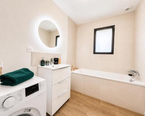 a white bathroom with a washing machine and a tub at Le Clos de Luc - 3 chambres - Jardin - Plage à 5 min in Luc-sur-Mer