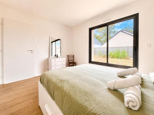 a bedroom with a large bed with a large window at Le Clos de Luc - 3 chambres - Jardin - Plage à 5 min in Luc-sur-Mer