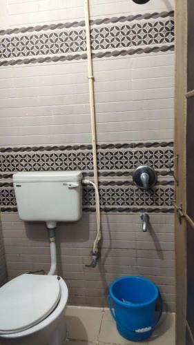 a bathroom with a toilet and a blue bucket at Triveni Inn in Jahāngīrābād