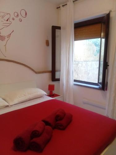 a bedroom with a red bed with a window at Il Sole Baunei by the sea in Santa Maria Navarrese