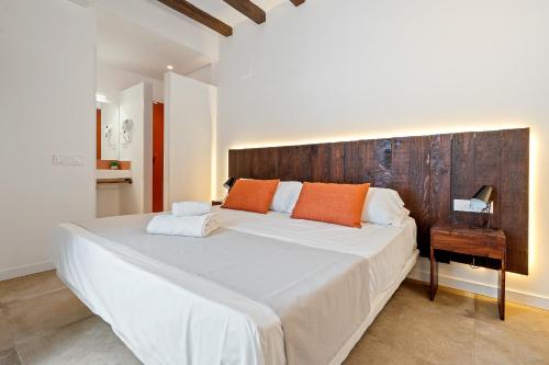 a bedroom with a large white bed with orange pillows at Port Apartsuite in Tarragona