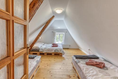 a attic bedroom with two beds and a window at Roubenka Kailas in Červená Voda