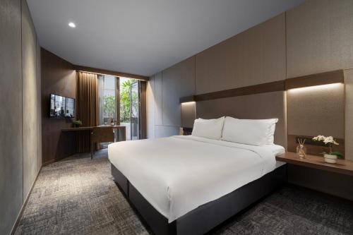 a bedroom with a large white bed and a desk at Oakwood Bencoolen Singapore in Singapore