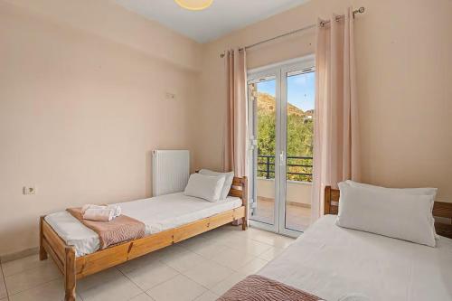 a bedroom with two beds and a large window at Dimitra Apartments Zakros Village in Kato Zakros