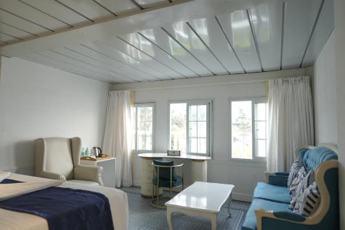 a bedroom with a bed and a couch and windows at State Beach Resort And Spa in Kannur