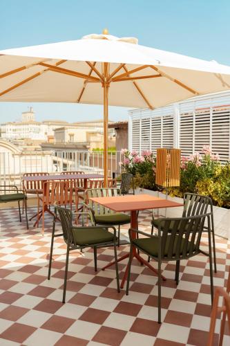 a patio with tables and chairs and an umbrella at Cloud 7 Roma Hotel in Rome