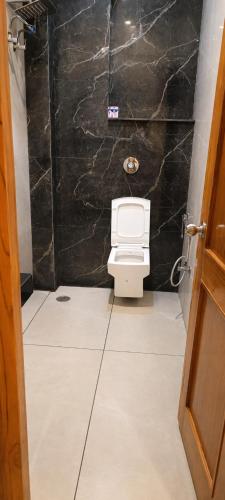 a bathroom with a toilet and a black wall at The Pearl Hotel Rampur in Rāmpur
