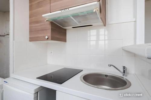 a white kitchen with a sink and a counter at Bright Studio Near Paris & Disneyland in Neuilly-Plaisance