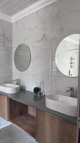 a bathroom with two sinks and two mirrors at Pine View Guesthouse Graskop in Graskop