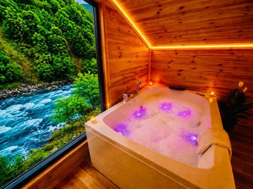 a bath tub in a room with a window at Ayder Royal River Resorts - Bungalows & Hotels in Çamlıhemşin