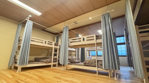 a room with three bunk beds and a wooden floor at ヨゴダステイアンドリトリート Yogoda Stay & Retreat in Ina