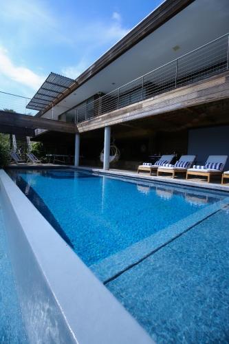 a large swimming pool with chairs and a building at Villa Scappà Porticcio - Piscine & vue mer in Grosseto-Prugna