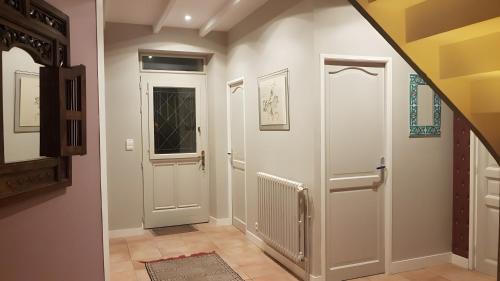 a hallway with a white door and a staircase at Chambre D'hôtes De La Vaine in Cartelègue
