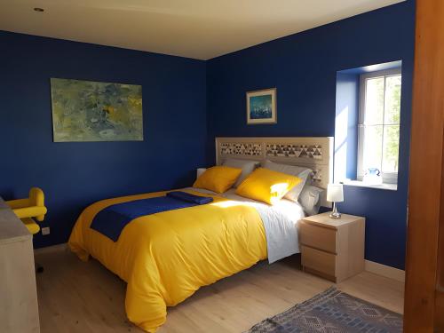 a bedroom with blue walls and a bed with yellow pillows at Chambre D'hôtes De La Vaine in Cartelègue