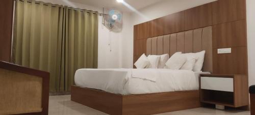 a bedroom with a large bed with a wooden headboard at Anchani Residency Rooms in Pāmbādi