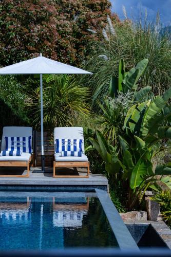 two chairs and an umbrella next to a pool at Villa Scappà Porticcio - Piscine & vue mer in Grosseto-Prugna