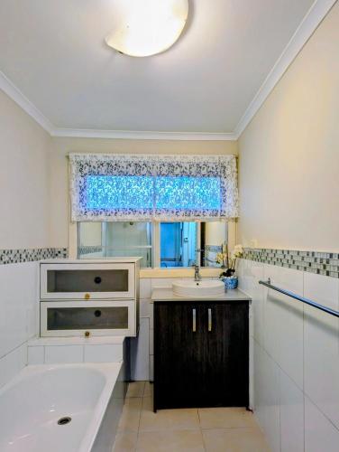 a bathroom with a sink and a tub and a window at Star House in Mitcham