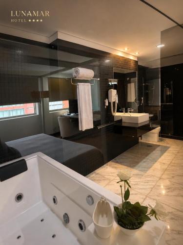 a bathroom with a large bathroom with a sink and a tub at Hotel Lunamar in Beira
