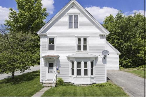a white house on a street with trees at GAGE FARMHOUSE LIMIT 6 apts in Bridgton