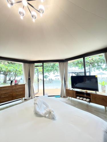 a bedroom with a bed and a tv and windows at Umbrella tree v1 in Nathon