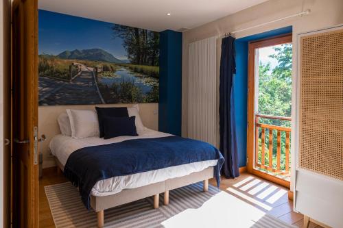 ein Schlafzimmer mit einem Bett und einem Gemälde an der Wand in der Unterkunft L'écrin des granges in Culoz