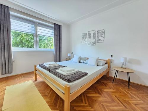 a white bedroom with a large bed in a room at Centar Apartman in Apatin