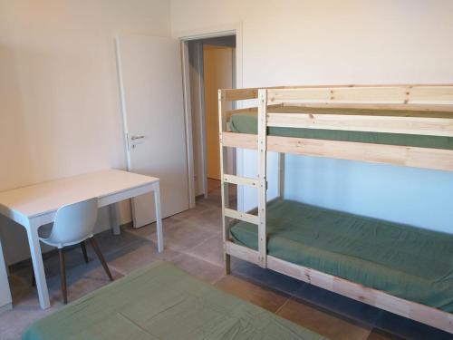 a room with bunk beds and a desk and a table at Ostello Postumia in Torre deʼ Picenardi