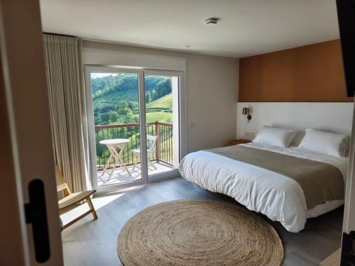 a bedroom with a large bed and a balcony at Kamiñone Landetxea in Beasain