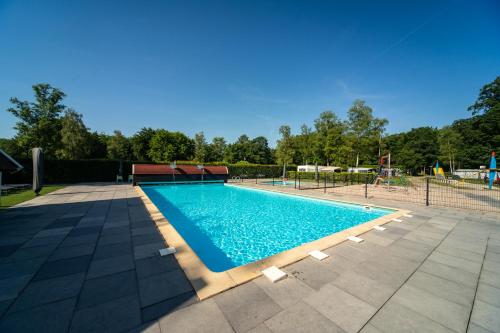 a swimming pool with a playground in the background at Koning te Rijk - Residence de Eese in De Bult