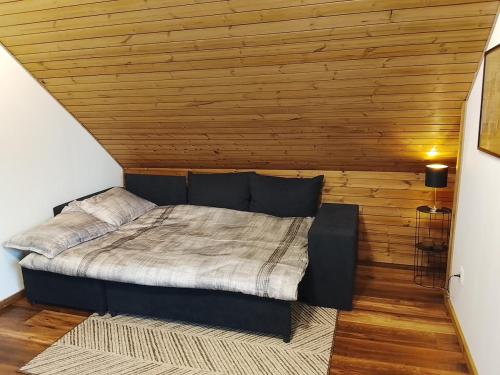 a bedroom with a bed with a wooden wall at Minija Stay Priekule 1925 in Priekulė