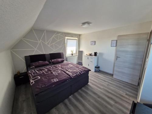 a bedroom with a bed with a purple comforter at Daniels Gästezimmer in Dockweiler