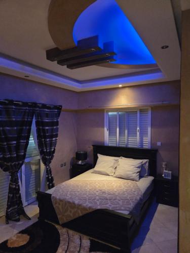a bedroom with a bed with a blue light on the ceiling at Dar mayssane in Agadir