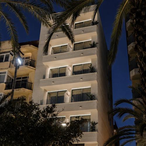 a building with palm trees in front of it at Suites by Miramar - Adults only in Lloret de Mar