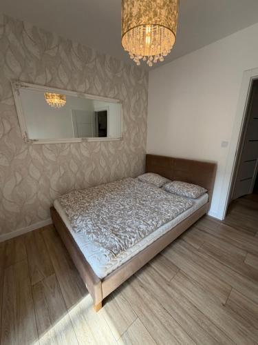 a bedroom with a bed and a mirror and a chandelier at Apartament Rejtana in Leszno