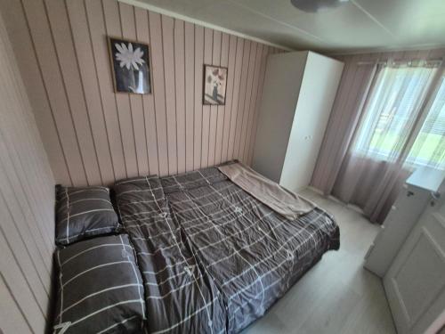 a bedroom with a bed with a comforter and a window at Cozy Home in Stokmarknes