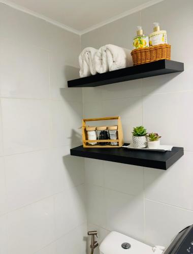 a bathroom with black shelves above a toilet at Bienvenida Condotel in Dumaguete