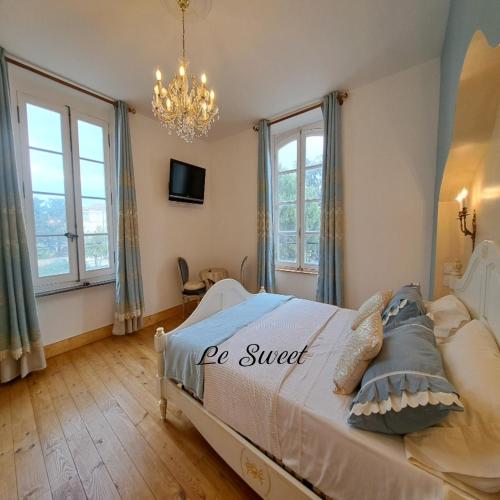 a bedroom with a bed with a chandelier and windows at La Maison du Canal- vue Canal- L'ère du Temps in Homps